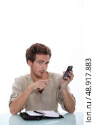 Man with a ringbound agenda pointing at a cellphone. Стоковое фото, агентство Ingram Publishing / Фотобанк Лори