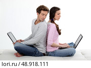 portrait of lovely young couple back-to-back with laptop. Стоковое фото, агентство Ingram Publishing / Фотобанк Лори