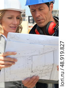 female architect and workman consulting blueprints in construction site. Стоковое фото, агентство Ingram Publishing / Фотобанк Лори