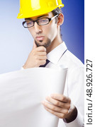 Young engineer looking at drawings. Стоковое фото, агентство Ingram Publishing / Фотобанк Лори