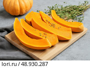 Cutting Fresh Pumpkins on Board. Baked pumpkin. Sliced raw Cucurbita maxima and spices for preparing soup, warm salad, fall dish. Thanksgiving food. Roasted vegetable in olive oil salt pepper, herbs. Стоковое AI-изображение, AI-художник Марина Демидюк / Фотобанк Лори