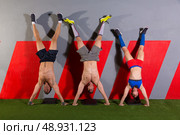Handstand push-up group pushups workout top position at gym. Стоковое фото, агентство Ingram Publishing / Фотобанк Лори