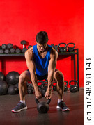 Kettlebell swing workout training man at gym with red walls. Стоковое фото, агентство Ingram Publishing / Фотобанк Лори