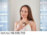 Middle-aged Woman Uses Massager for Skin Rejuvenation in Bright Indoor Setting. Стоковое фото, фотограф Aleksandr Golubev / Фотобанк Лори