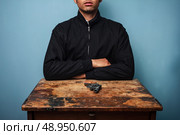Dangerous man at table with a gun. Стоковое фото, агентство Ingram Publishing / Фотобанк Лори