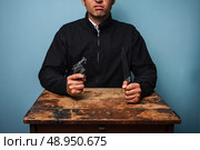 Dangerous man at table with a knife and a gun. Стоковое фото, агентство Ingram Publishing / Фотобанк Лори