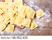Raw ravioli with flour on wooden table. Стоковое фото, агентство Ingram Publishing / Фотобанк Лори