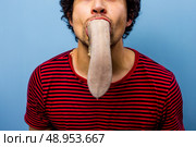 Young man with an ox tongue in his mouth. Стоковое фото, агентство Ingram Publishing / Фотобанк Лори