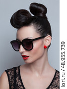 Fashionable model in trendy sunglasses. Plastic skin. Portraiture. Red lips. Updo, twisted high bun. top knot. Стоковое фото, агентство Ingram Publishing / Фотобанк Лори