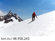 Climber standing on a glacier looking at a mountain peak. Dent du Geant, Mont Blanc, Chamonix, France. Стоковое фото, агентство Ingram Publishing / Фотобанк Лори