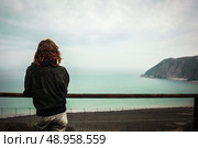 Young woman is admiring the seaside view from a hill. Стоковое фото, агентство Ingram Publishing / Фотобанк Лори