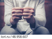 Young man is sitting on a sofa with his fists clenched. Стоковое фото, агентство Ingram Publishing / Фотобанк Лори