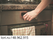 The hand of a young woman is turning the knob on a stove. Стоковое фото, агентство Ingram Publishing / Фотобанк Лори
