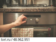 The hand of a young woman is turning the knob on a stove. Стоковое фото, агентство Ingram Publishing / Фотобанк Лори