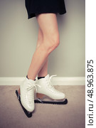 Young woman is wearing ice skates at home with blade guards to wear them in. Стоковое фото, агентство Ingram Publishing / Фотобанк Лори
