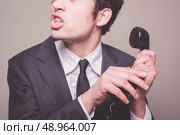 Young businessman is hushing someone in order to hear the phone. Стоковое фото, агентство Ingram Publishing / Фотобанк Лори