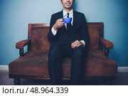 Young businessman drinking coffee on a sofa. Стоковое фото, агентство Ingram Publishing / Фотобанк Лори