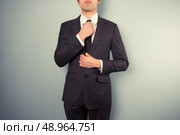 A young businessman is adjusting his tie. Стоковое фото, агентство Ingram Publishing / Фотобанк Лори