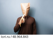 Young ma with bag over head eating banana. Стоковое фото, агентство Ingram Publishing / Фотобанк Лори