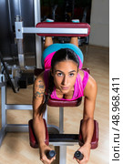 Lying hamstring curl machine girl brunette woman. Стоковое фото, агентство Ingram Publishing / Фотобанк Лори