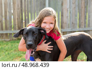 great dane and kid girl hug playing together at backyard outdoor. Стоковое фото, агентство Ingram Publishing / Фотобанк Лори