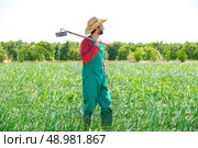 Farmer man with hoe looking at his orchard field with hat. Стоковое фото, агентство Ingram Publishing / Фотобанк Лори