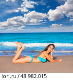 Brunette tourist lying in beach sand tanning happy in summer vacation. Стоковое фото, агентство Ingram Publishing / Фотобанк Лори
