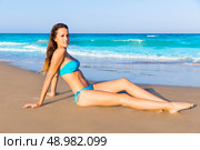Brunette tourist sitting in tropical beach sand tanning happy in summer vacation. Стоковое фото, агентство Ingram Publishing / Фотобанк Лори