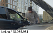 Guy studies scene of the accident, where the car collided with another, to assess the potential damage and the cost of repairs. Стоковое видео, видеограф Strunov David / Фотобанк Лори