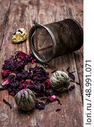 tea strainer and different varieties of tea leaves on wooden background.The toned image. Стоковое фото, агентство Ingram Publishing / Фотобанк Лори