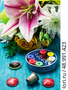 sewing accessories with a bouquet of fresh flowers on turquoise background. Стоковое фото, агентство Ingram Publishing / Фотобанк Лори