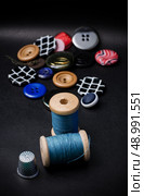thread and buttons for sewing master on black background.Selective focus. working tool dressmaker. Стоковое фото, агентство Ingram Publishing / Фотобанк Лори