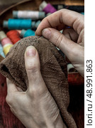 women's hands in the process stepania holey socks on the background of sewing thread. Стоковое фото, агентство Ingram Publishing / Фотобанк Лори