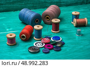 thread buttons for crafts on turquoise wooden background.Selective focus. working tool dressmaker. Стоковое фото, агентство Ingram Publishing / Фотобанк Лори