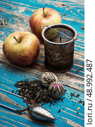 tea leaves and red apple on wooden background.The image is tinted in vintage style. Стоковое фото, агентство Ingram Publishing / Фотобанк Лори