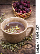 ceramic cup brewed with rose hips and chamomile in vintage rustic style. healing broth. Стоковое фото, агентство Ingram Publishing / Фотобанк Лори