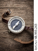 obsolete compass . obsolete compass with leather strap on wooden table top in retro style. Стоковое фото, агентство Ingram Publishing / Фотобанк Лори