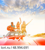 young group having fun on the beach playing guitar and dancing in a convertible car. Стоковое фото, агентство Ingram Publishing / Фотобанк Лори