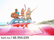 young group having fun on the beach playing guitar and dancing in a convertible car. Стоковое фото, агентство Ingram Publishing / Фотобанк Лори