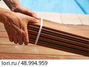 Ipe decking installation with carpenter hands holding tropical wood slats. Стоковое фото, агентство Ingram Publishing / Фотобанк Лори