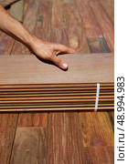 Ipe decking installation with carpenter hands holding tropical wood slats. Стоковое фото, агентство Ingram Publishing / Фотобанк Лори