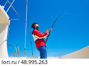 Beard sailor man fishing rod trolling in saltwater in a boat trolling with captain cap. Стоковое фото, агентство Ingram Publishing / Фотобанк Лори