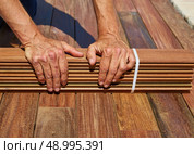 Ipe decking installation with carpenter hands holding tropical wood slats. Стоковое фото, агентство Ingram Publishing / Фотобанк Лори