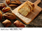 Bread varied loafs sliced on wood board in rustic wood table. Стоковое фото, агентство Ingram Publishing / Фотобанк Лори