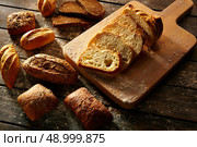 Bread varied loafs sliced on wood board in rustic wood table. Стоковое фото, агентство Ingram Publishing / Фотобанк Лори