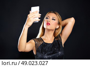 Blond fashion woman smartphone selfie in black background. Стоковое фото, агентство Ingram Publishing / Фотобанк Лори