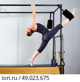 Pilates woman in cadillac split legs stretch exercise at gym. Стоковое фото, агентство Ingram Publishing / Фотобанк Лори