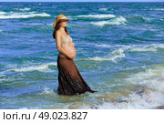 Pregnant woman on the beach playing with waves. Стоковое фото, агентство Ingram Publishing / Фотобанк Лори