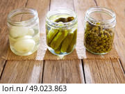 bottled pickles as capers onion and cucumbers in wooden table. Стоковое фото, агентство Ingram Publishing / Фотобанк Лори
