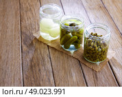 bottled pickles as capers onion and cucumbers in wooden table. Стоковое фото, агентство Ingram Publishing / Фотобанк Лори